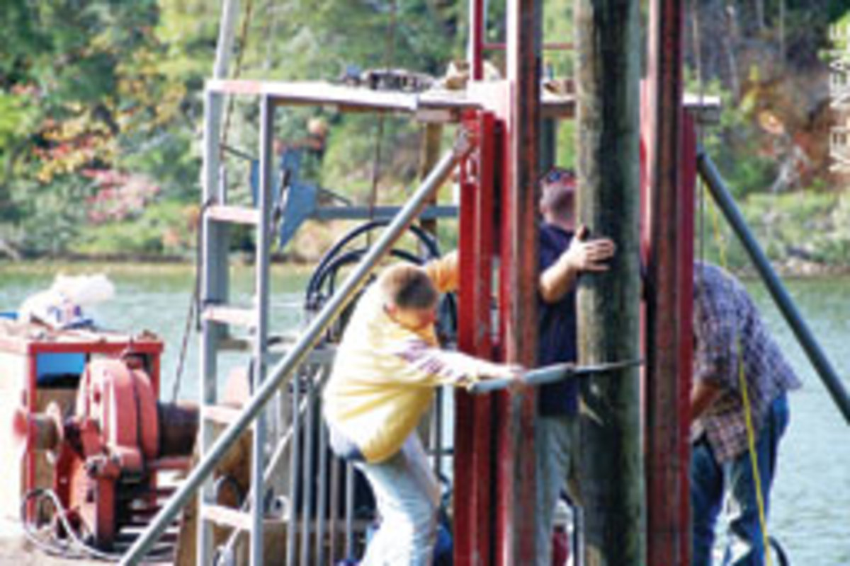 Frankie Davis (left) and helpers check and adjust the position of a piling.
