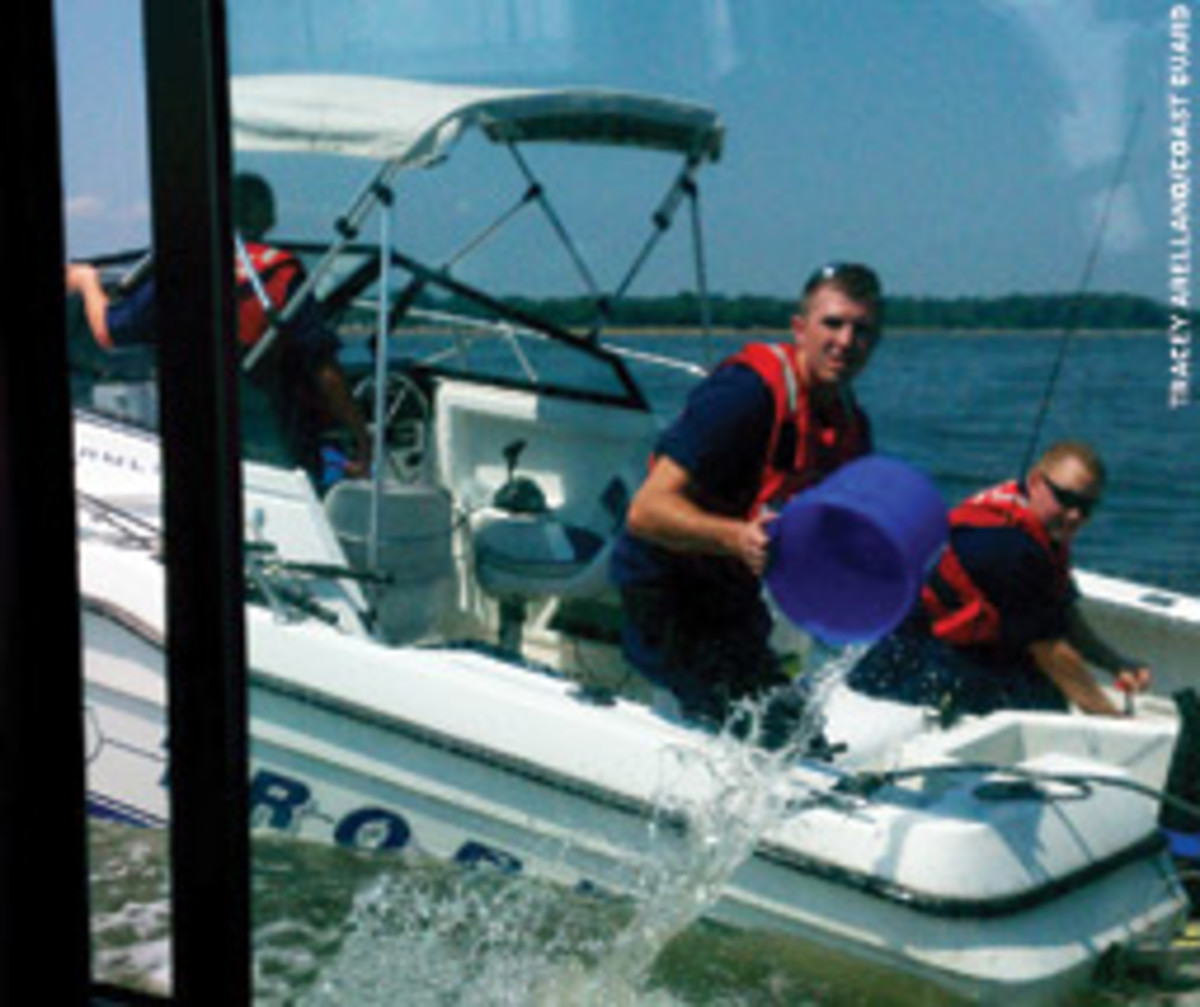 Crewmenbers from Coast Guard Station Annapolis bail a 23-foot powerboat as it is towed to shore.