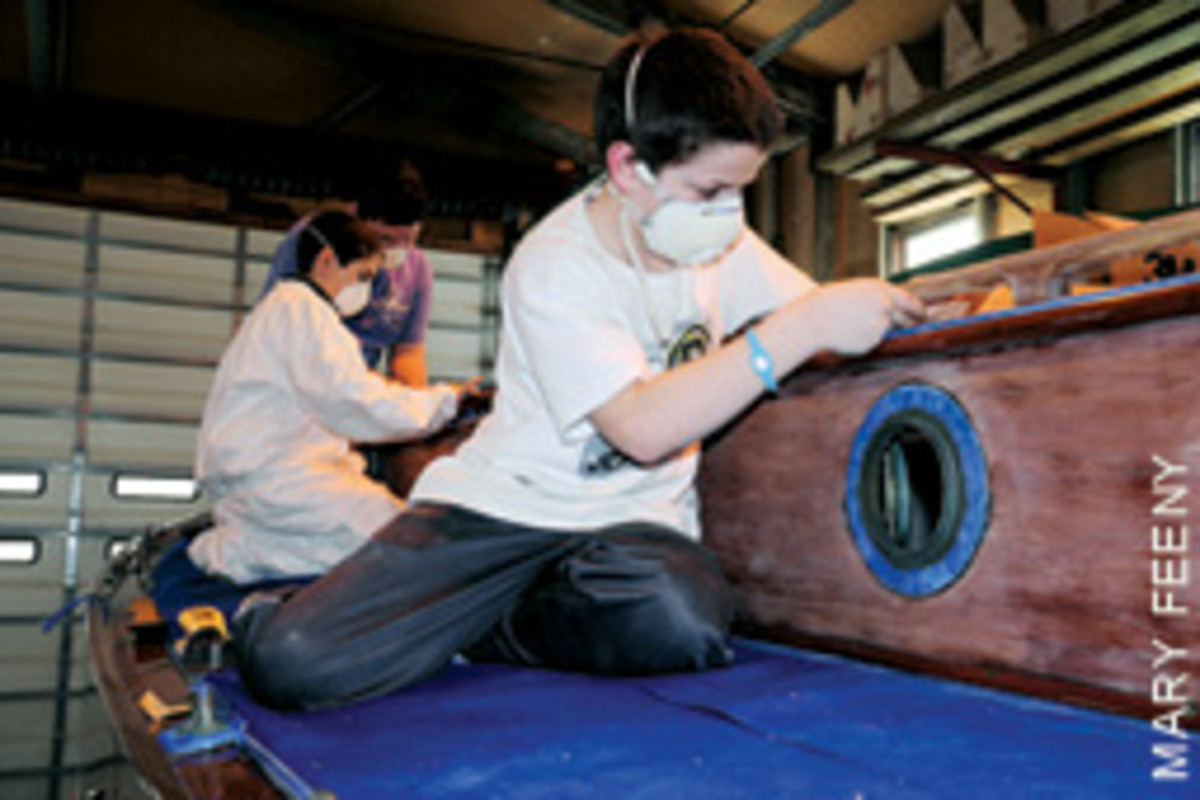 Students in the Herreshoff Institute's After-School Boat Shop Program prep a boat for varnish.