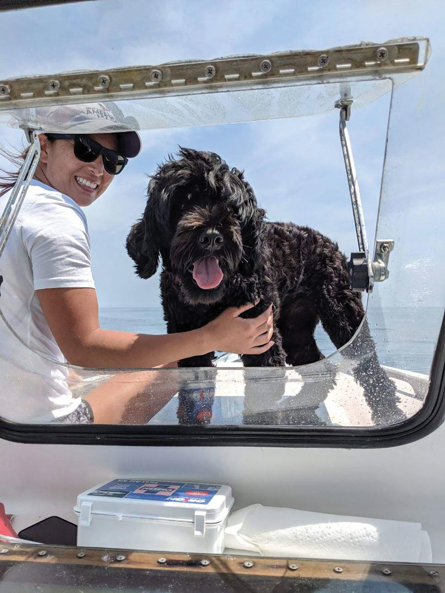 Amy Parks and the couple’s Portuguese Water Dog, Gennaker (Genny for short), sitting on the bow