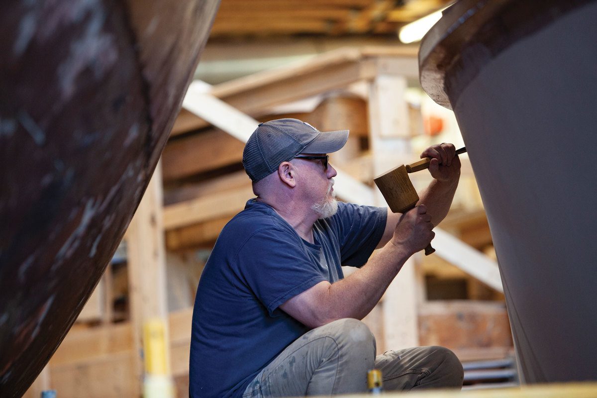 Hayden at Brooklin Boat Yard, carving a scroll into the bow of a new 49-foot river boat