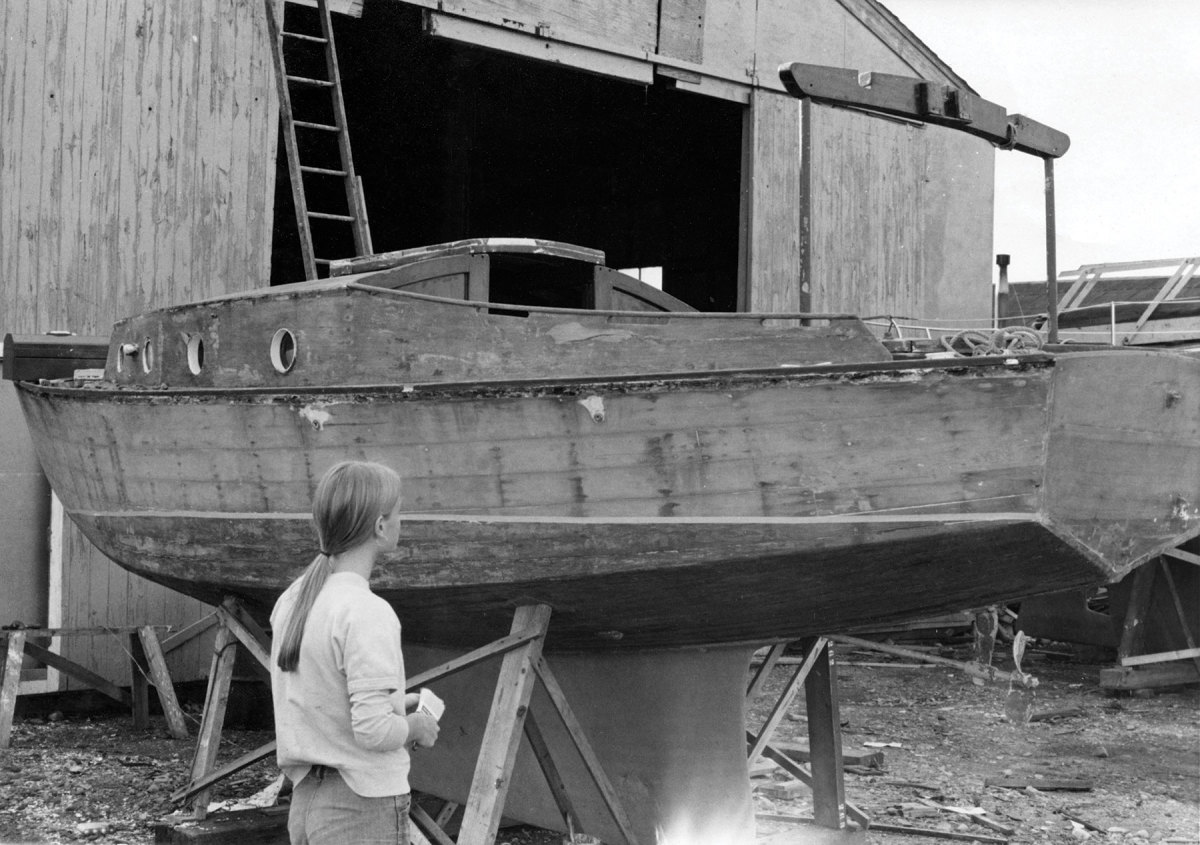A friend of the boys admires the work they did on the Pennant, stripping the topsides and the hull bottom. 